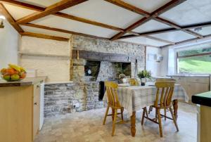 a kitchen with a table and chairs and a stone fireplace at 2 bed rural retreat nestled in the heart of Exmoor in Parracombe