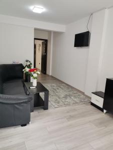 uma sala de estar com um sofá preto e uma televisão em Apartament Sonya em Bucareste