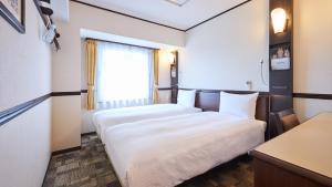 ein Hotelzimmer mit 2 Betten und einem Fenster in der Unterkunft Toyoko Inn Tokyo Nihombashi Zeimusho Mae in Tokio