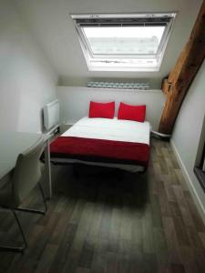 una camera da letto con un letto con cuscini rossi e una finestra di Studio hypercentre ralliement ad Angers