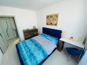 a small bedroom with a blue bed and a desk at La Ursi in Onești