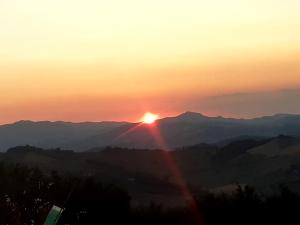 un tramonto su una catena montuosa con un arcobaleno di B&B Casa dei Cuori - Natura, Silenzio, relax a 550 m di quota a Langhirano