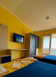 een kamer met 2 bedden en een tv aan een gele muur bij Apartmani Lukšić in Sutomore