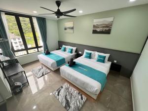 a bedroom with two beds and a ceiling fan at BEATRIX HOTEL in Brinchang