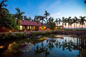 a house with a pond with palm trees in front of it at Viet House Yen Duc Village in Tử Lạc
