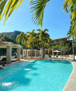 a swimming pool with palm trees and a building at Pico De Loro 2BR Carola B Unit with Lagoon View in Nasugbu
