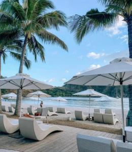a beach with white lounge chairs and umbrellas at Pico De Loro 2BR Carola B Unit with Lagoon View in Nasugbu