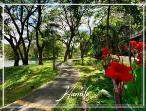 a path through a park with red flowers and trees at Pico De Loro 2BR Carola B Unit with Lagoon View in Nasugbu