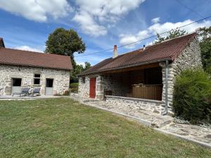 a stone house with a red door and a yard at Gite La Fileuse in Saint-Plantaire