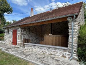 una pequeña casa de piedra con una puerta roja y una puerta roja en Gite La Fileuse, en Saint-Plantaire