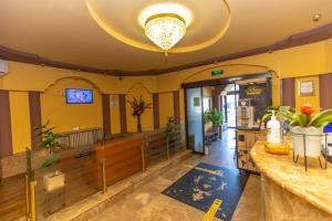 a lobby of a restaurant with yellow walls and a chandelier at Hotel Sir Gara de Nord in Bucharest