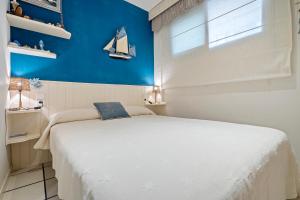 a bedroom with a white bed and a blue wall at Hauzify I Apartament Capellans in Salou