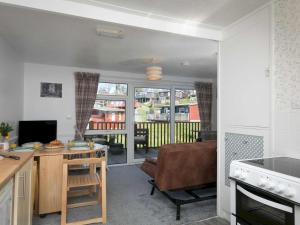 eine Küche und ein Wohnzimmer mit einem Tisch und einem Sofa in der Unterkunft Pass the Keys Comfortable 2 Bed Riverside Chalet near Snowdonia in Caernarfon
