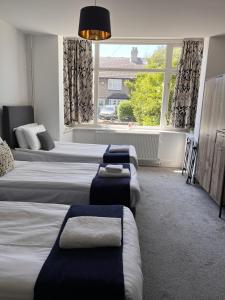 a hotel room with three beds and a window at North Cambridge Guesthouse by Payman Club in Cambridge