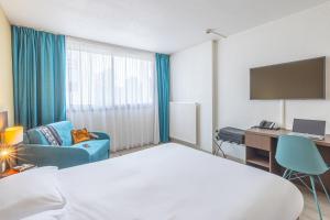 a hotel room with a bed and a tv at Les Loges du Park in Aix-les-Bains