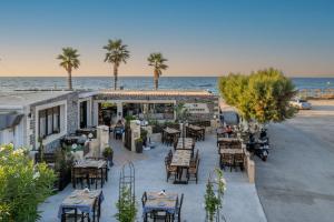 an outdoor restaurant with tables and chairs next to the ocean at Myra Mare Suites by Estia in Amoudara Herakliou