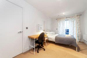 ein Schlafzimmer mit einem Schreibtisch, einem Bett und einem Bett sowie einem Fenster in der Unterkunft Spacious Modern 3 BR Apt w Balcony, Woolwich in Woolwich