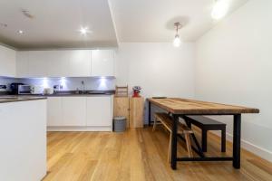 eine Küche mit weißen Schränken und einem Holztisch in der Unterkunft Spacious Modern 3 BR Apt w Balcony, Woolwich in Woolwich