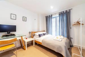 a bedroom with a bed and a desk and a window at Spacious Modern 3 BR Apt w Balcony, Woolwich in Woolwich