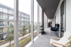 einen Balkon mit 2 Stühlen und großen Fenstern in der Unterkunft Spacious Modern 3 BR Apt w Balcony, Woolwich in Woolwich