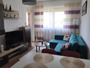 uma sala de estar com um sofá azul e uma televisão em Apartament Gardena Olsztyn Jaroty em Olsztyn