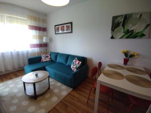 a living room with a blue couch and a table at Apartament Gardena Olsztyn in Olsztyn