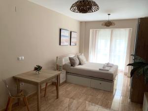 Schlafzimmer mit einem Bett, einem Tisch und einem Fenster in der Unterkunft Apartamentos Hernán Cortés in Villanueva de la Serena