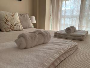 - Toalla blanca en una cama con 2 toallas enrolladas en Apartamentos Hernán Cortés, en Villanueva de la Serena