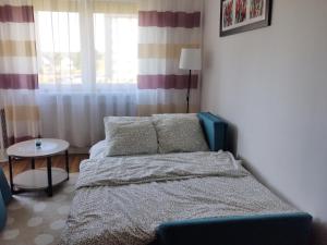 a bedroom with a bed and a table and a window at Apartament Gardena Olsztyn in Olsztyn
