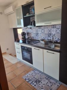 una cocina con armarios blancos y fregadero en AtticoCinque, en Bari
