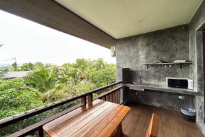 balcón con banco de madera y microondas en Tann Anda Resort en Thalang