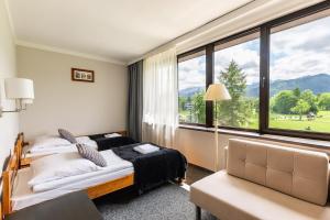 um quarto com uma cama e uma grande janela em Hotel Helios em Zakopane