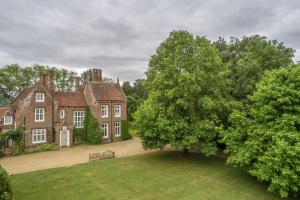 an old house with a tree in front of it at Old Rectory and Coach House in North Tuddenham