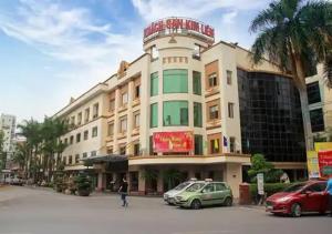 河內的住宿－Kim Liên - Số 7 Đào Duy Anh - by Bay Luxury Hotel，一座大型建筑,前面有汽车停放