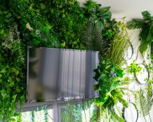 ściana pokryta zielonymi roślinami i telewizor w obiekcie Cocooning Romance in Leicester w mieście Leicester