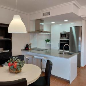 cocina con mesa y fregadero en Apartamento con jardín en Altaona Golf en Murcia