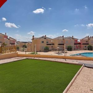 un patio con césped verde y una piscina y casas en Apartamento con jardín en Altaona Golf en Murcia