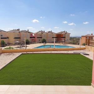 un patio de hierba con piscina y casas en Apartamento con jardín en Altaona Golf en Murcia