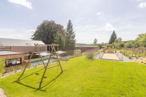 um jardim com um baloiço na relva em Villa Wood - Gîte de prestige en Ardennes - 10 personnes - Sauna, jacuzzi, piscine et billard em Tenneville
