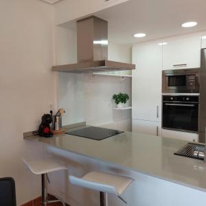 una cocina con encimera con taburetes. en Apartamento con jardín en Altaona Golf en Murcia