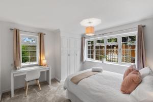 sypialnia z łóżkiem, biurkiem i oknami w obiekcie Silver Stag Properties, Luxurious 3 BR Bungalow w mieście Worthington