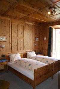 a bedroom with two beds in a room with wooden walls at Albergo Piz Cam in Vicosoprano