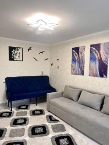 a living room with a couch and paintings on the wall at 2-х комнатная квартира в центре in Almaty
