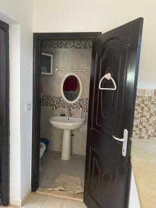 uma casa de banho com um lavatório e uma porta preta em Kimo rooms em Nabeul