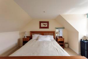 ein Schlafzimmer mit einem weißen Bett und zwei Nachttischen in der Unterkunft Blackhill Farm Cottage in Perth