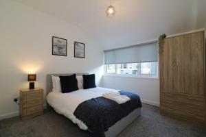 a bedroom with a bed and a dresser and a window at Signature - Alder View in Cumbernauld