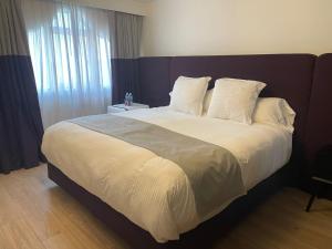 um quarto com uma cama grande com lençóis brancos e almofadas em Casa Amari em Cidade do México
