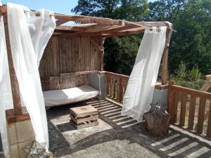 eine hölzerne Pergola mit einem Bett auf einer Terrasse in der Unterkunft Appartement en bordure de forêt in Cransac