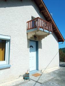 ein weißes Haus mit einem Balkon über einer Tür in der Unterkunft Appartement en bordure de forêt in Cransac