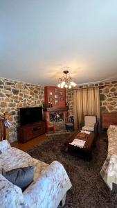 un soggiorno con 2 divani e un muro di pietra di Mountain View - Full Villa a Polydrosos